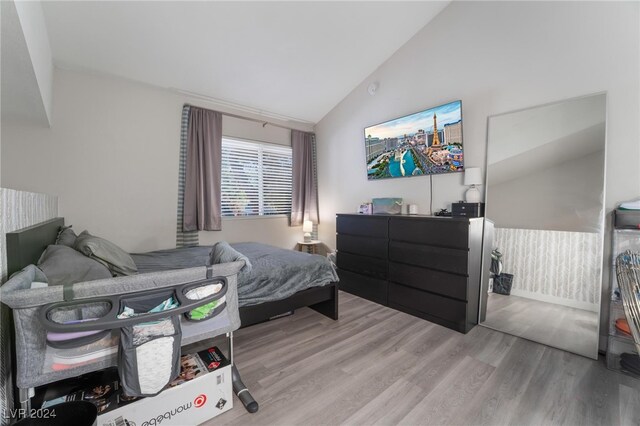 bedroom with high vaulted ceiling and wood-type flooring