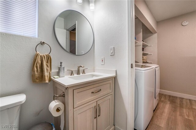 bathroom featuring washing machine and clothes dryer, vanity, hardwood / wood-style floors, and toilet