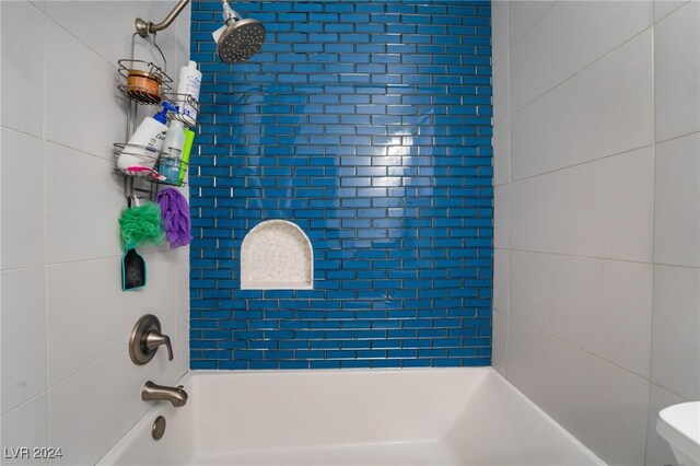 bathroom featuring tiled shower / bath and toilet