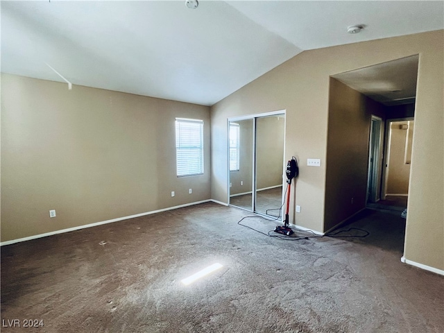 unfurnished bedroom featuring dark carpet and vaulted ceiling