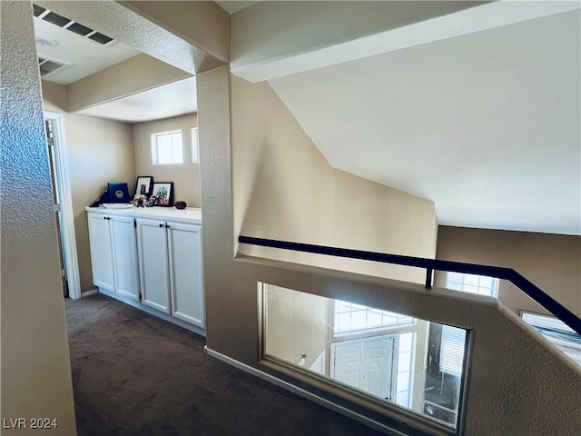 interior space with dark carpet and vaulted ceiling