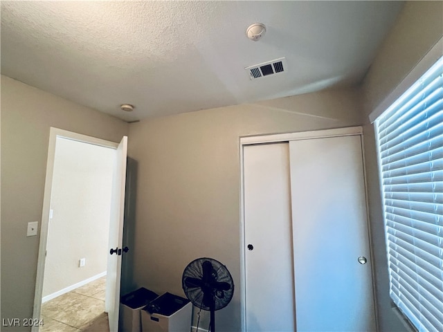 unfurnished bedroom with a textured ceiling, light tile patterned floors, and a closet