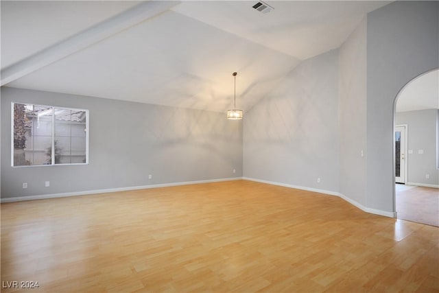 empty room with beam ceiling, light hardwood / wood-style floors, and high vaulted ceiling