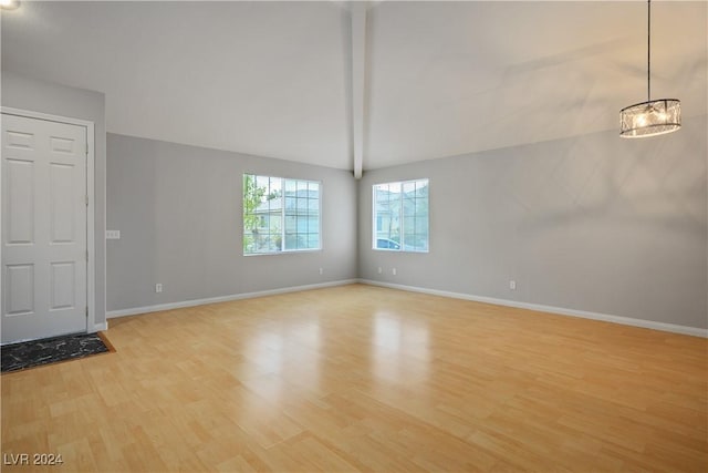 interior space featuring lofted ceiling with beams, light hardwood / wood-style floors, and an inviting chandelier