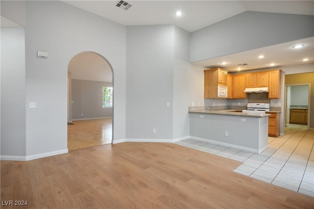 kitchen with white appliances, high vaulted ceiling, light wood-type flooring, light brown cabinetry, and kitchen peninsula