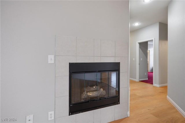 interior details with a tile fireplace and wood-type flooring