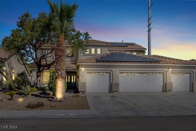 mediterranean / spanish-style house with a garage and solar panels