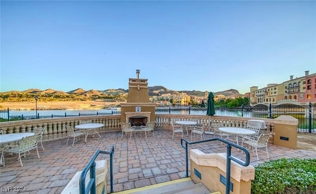 view of patio / terrace with exterior fireplace and a water and mountain view