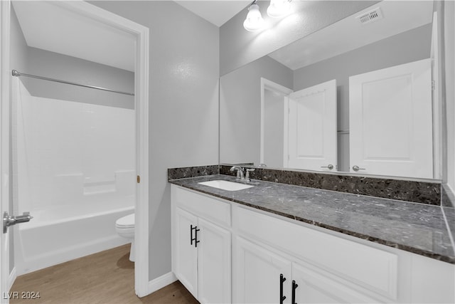 full bathroom featuring hardwood / wood-style floors, bathing tub / shower combination, vanity, and toilet