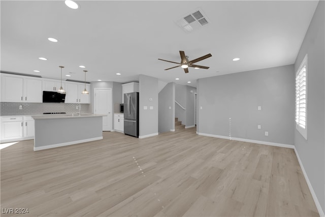 kitchen featuring appliances with stainless steel finishes, light wood-type flooring, white cabinetry, and pendant lighting