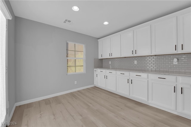 kitchen featuring white cabinets, light hardwood / wood-style floors, and tasteful backsplash