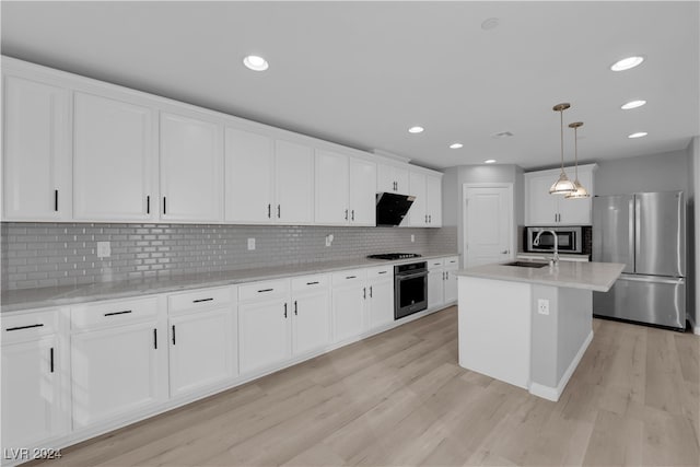 kitchen featuring light hardwood / wood-style flooring, stainless steel appliances, a center island with sink, and decorative light fixtures