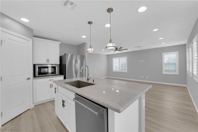 kitchen with a center island with sink, light stone counters, stainless steel appliances, and a wealth of natural light