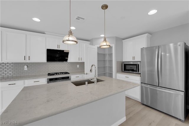 kitchen featuring appliances with stainless steel finishes, white cabinetry, sink, and extractor fan