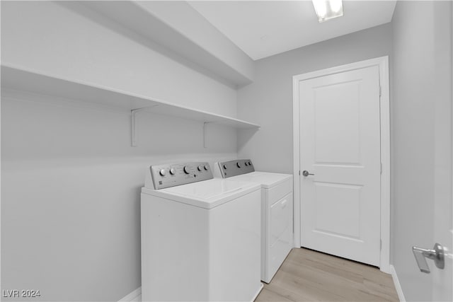 laundry room with washer and clothes dryer and light hardwood / wood-style flooring