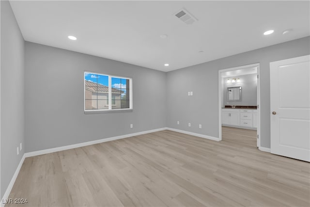 unfurnished bedroom with light hardwood / wood-style flooring and connected bathroom