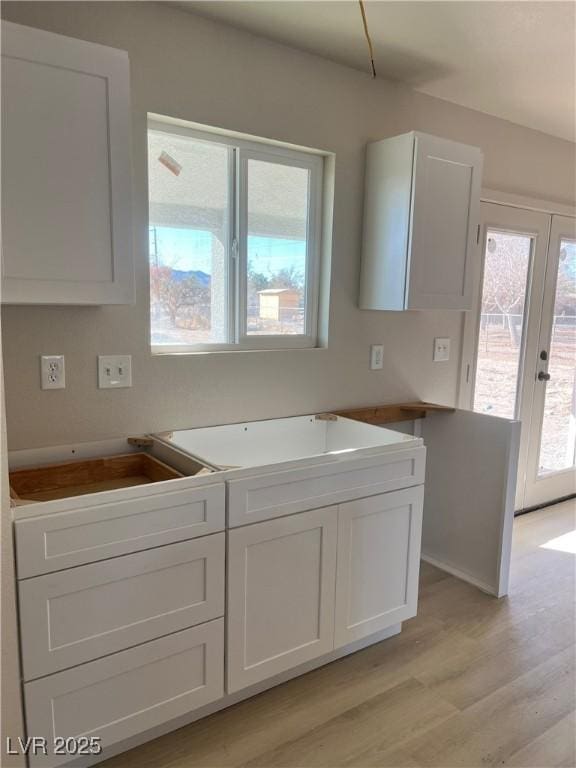 kitchen with french doors, white cabinets, and light wood-style floors