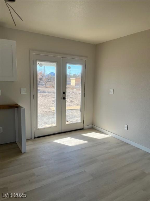 doorway featuring french doors, light wood-type flooring, and baseboards