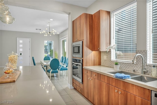 kitchen featuring a wealth of natural light, appliances with stainless steel finishes, hanging light fixtures, and sink