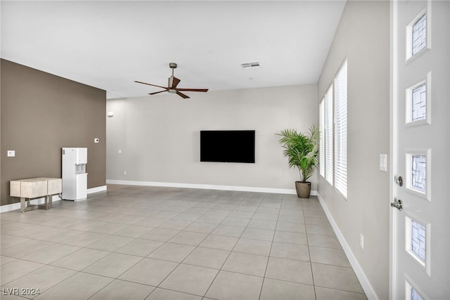 unfurnished living room with ceiling fan, plenty of natural light, and light tile patterned floors