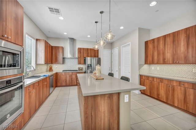 kitchen with stainless steel appliances, sink, a kitchen island, wall chimney range hood, and pendant lighting