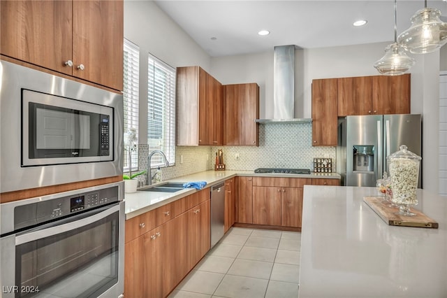 kitchen with stainless steel appliances, wall chimney range hood, light tile patterned floors, hanging light fixtures, and sink