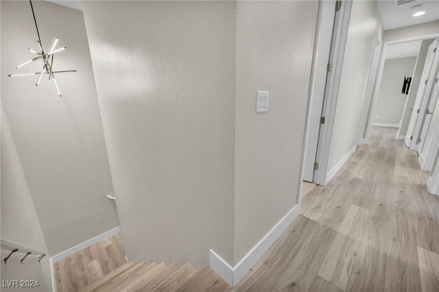 hall with light hardwood / wood-style floors and a chandelier