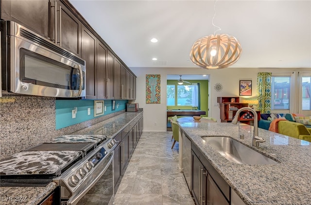 kitchen featuring light stone countertops, appliances with stainless steel finishes, dark brown cabinets, and sink