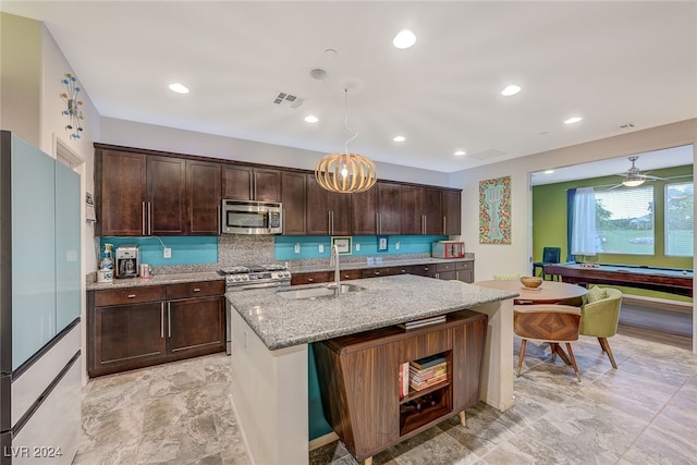 kitchen featuring sink, an island with sink, dark brown cabinets, light stone counters, and stainless steel appliances