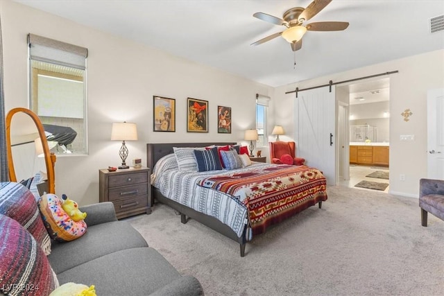 carpeted bedroom with ceiling fan, ensuite bathroom, and a barn door