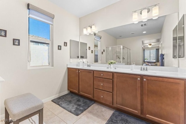 bathroom with a shower with door, vanity, a healthy amount of sunlight, and tile patterned floors