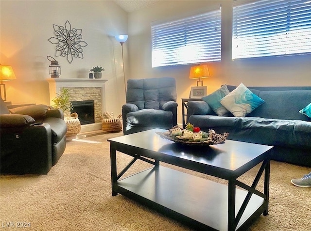 living room featuring a stone fireplace and carpet flooring