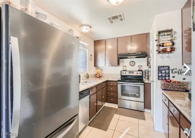 kitchen featuring light stone countertops, sink, light tile patterned floors, and stainless steel appliances