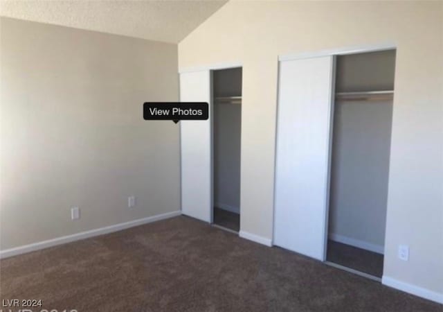 unfurnished bedroom featuring dark carpet, lofted ceiling, and a textured ceiling