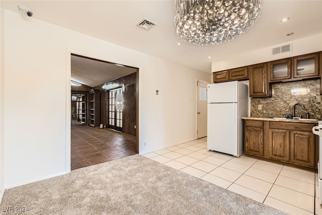 kitchen with light carpet, sink, decorative backsplash, white fridge, and a chandelier