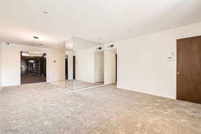 carpeted empty room with a chandelier