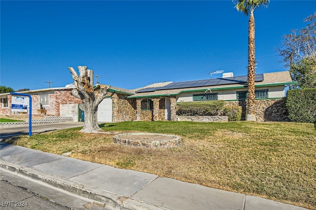 ranch-style home featuring solar panels, a front yard, and a garage