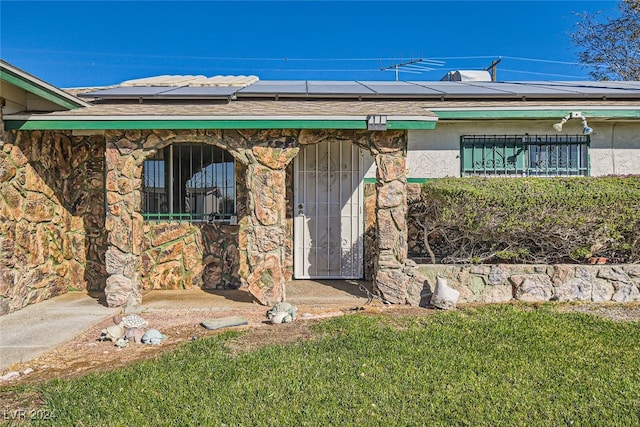 property entrance with a lawn and solar panels