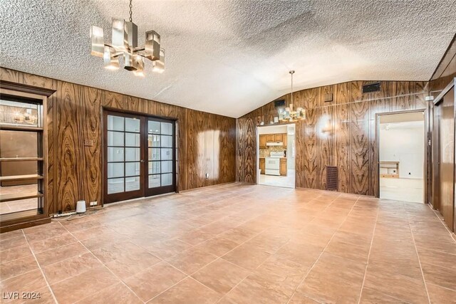 408 Rossmoyne Ave, North Las Vegas, NV 89030 - unfurnished living room featuring a chandelier, wooden walls, lofted ceiling, french doors, and a textured ceiling