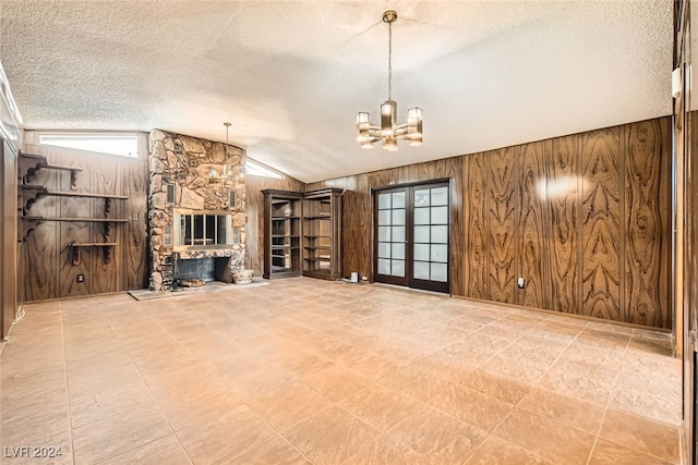 unfurnished living room featuring a fireplace, lofted ceiling, a textured ceiling, and wooden walls