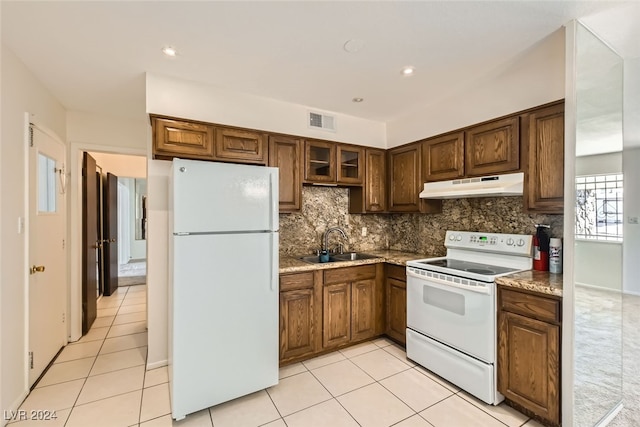 kitchen with sink, tasteful backsplash, light stone counters, white appliances, and light tile patterned flooring