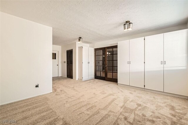 408 Rossmoyne Ave, North Las Vegas, NV 89030 - unfurnished bedroom featuring light colored carpet, multiple closets, a textured ceiling, french doors, and baseboards