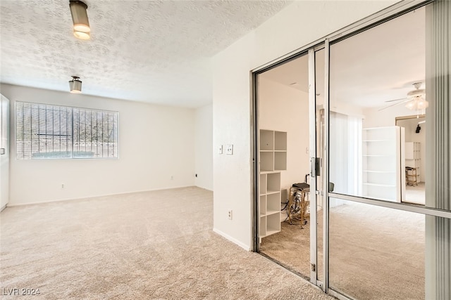 carpeted empty room featuring a textured ceiling and ceiling fan