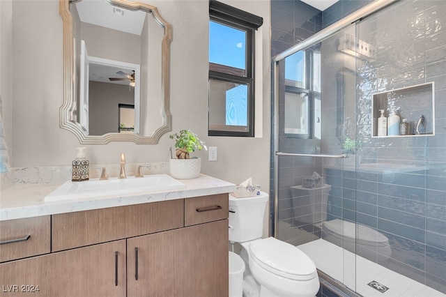 bathroom featuring vanity, ceiling fan, toilet, and an enclosed shower