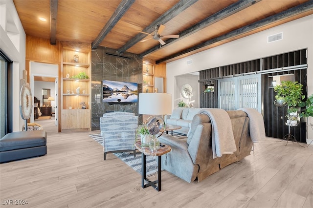 living room with wood ceiling, beamed ceiling, built in features, light wood-type flooring, and ceiling fan