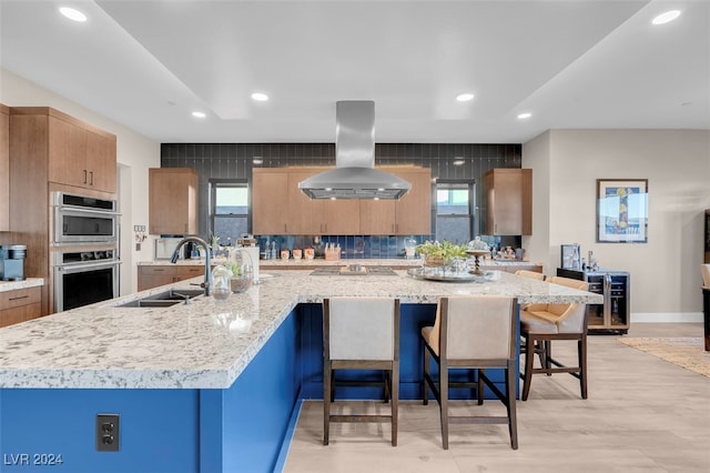 kitchen with island range hood, a kitchen breakfast bar, a large island, and plenty of natural light