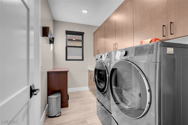 laundry room featuring independent washer and dryer, cabinets, and light hardwood / wood-style floors