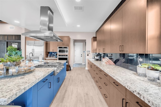 kitchen with appliances with stainless steel finishes, light stone countertops, island range hood, and light wood-type flooring