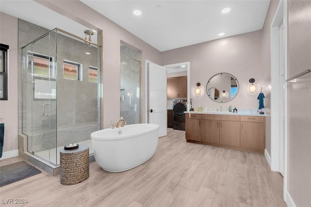 bathroom with vanity, hardwood / wood-style floors, independent shower and bath, and washer / clothes dryer