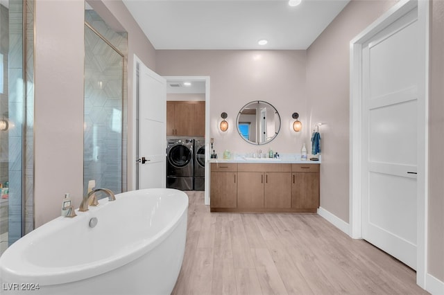 bathroom with vanity, washer and clothes dryer, plus walk in shower, and hardwood / wood-style flooring